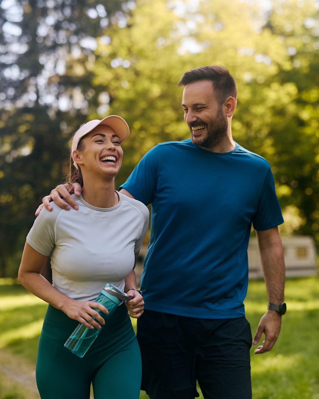 A couple laughing together on a walk through a sunlit park