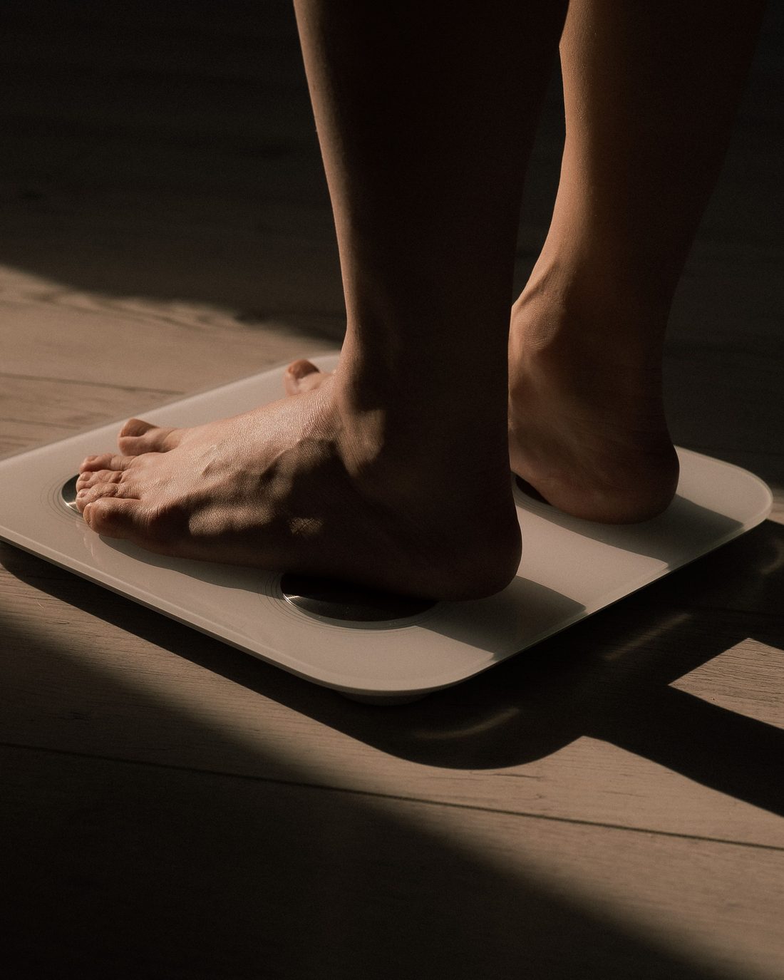 Bare feet on a bathroom scale in low morning light